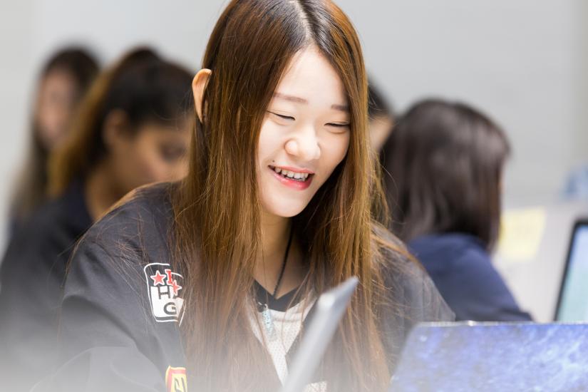 UTS College students smiling while looking at a computer