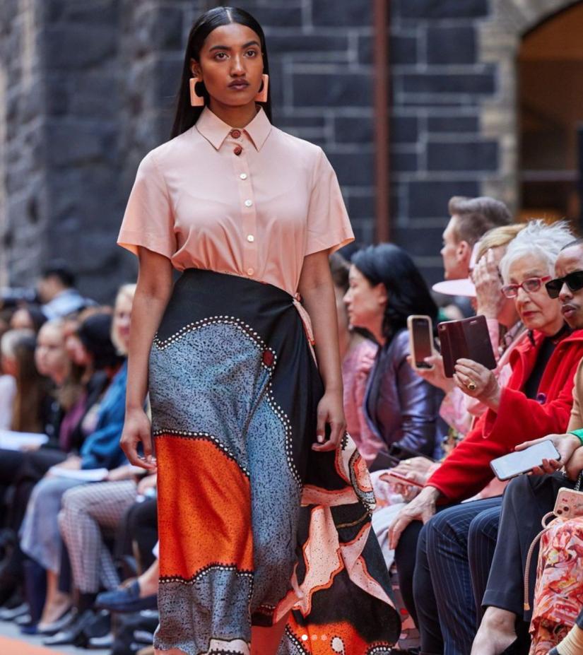 Woman walking down a catwalk wearing a Ngali shirt and silk scarf as a skirt