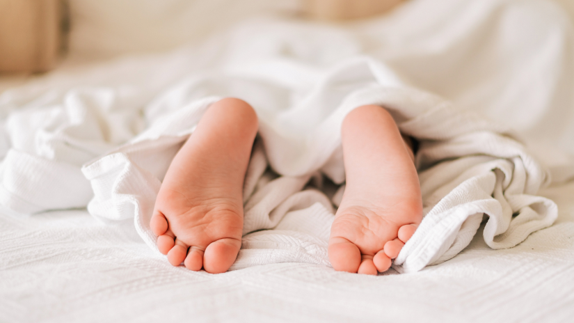 A picture of a child's feet covered in blanket as if the child is sleeping on a bed