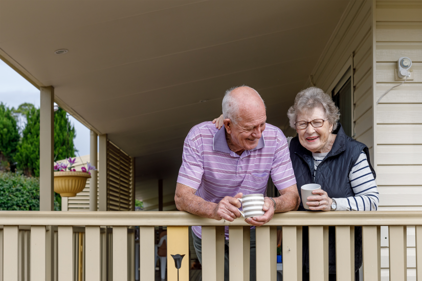 Two elderly people enjoying a cup of tea on their porch