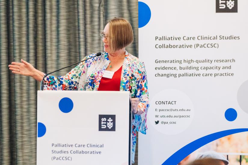 Woman talking at a podium in front of a UTS PaCCSC sign