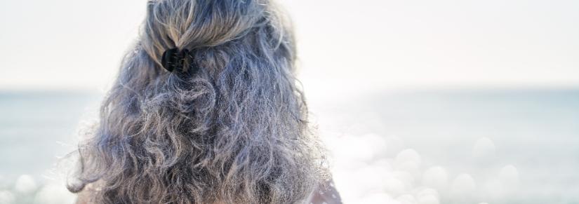 Middle age woman standing on back view at seaside. Image: Adobe Stock