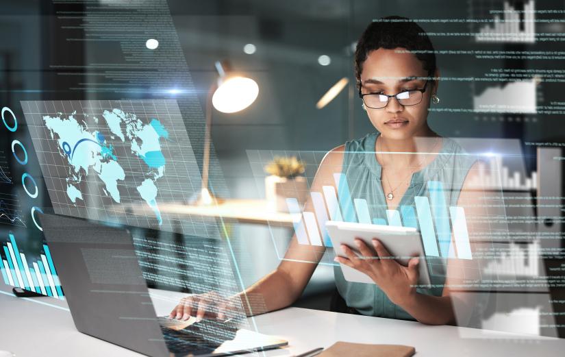 Adobe stock picture of a young woman working with digital devices with graphic overlays screen displays.