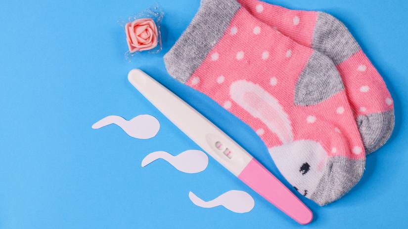 pregnancy test with baby socks and sperm shapes.