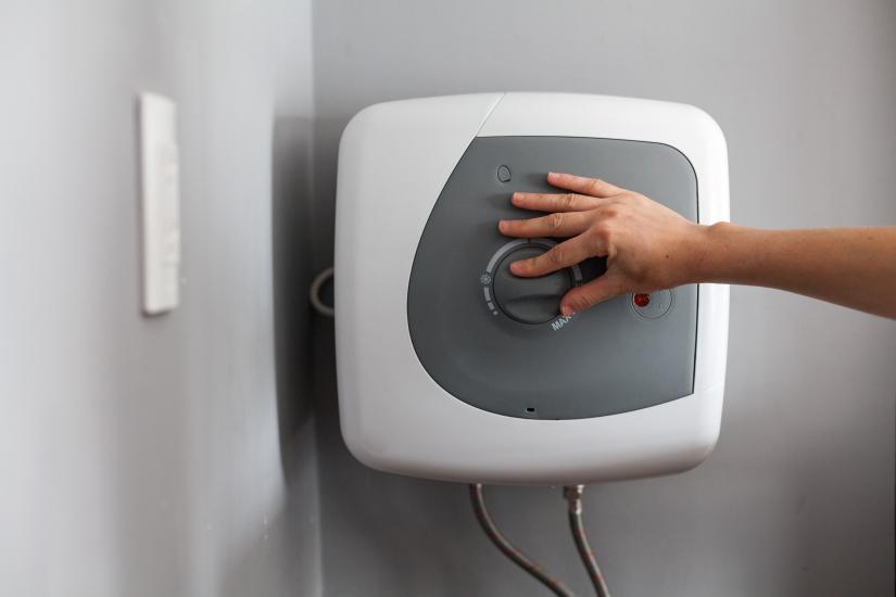 Women adjusting temperature on electric water heater