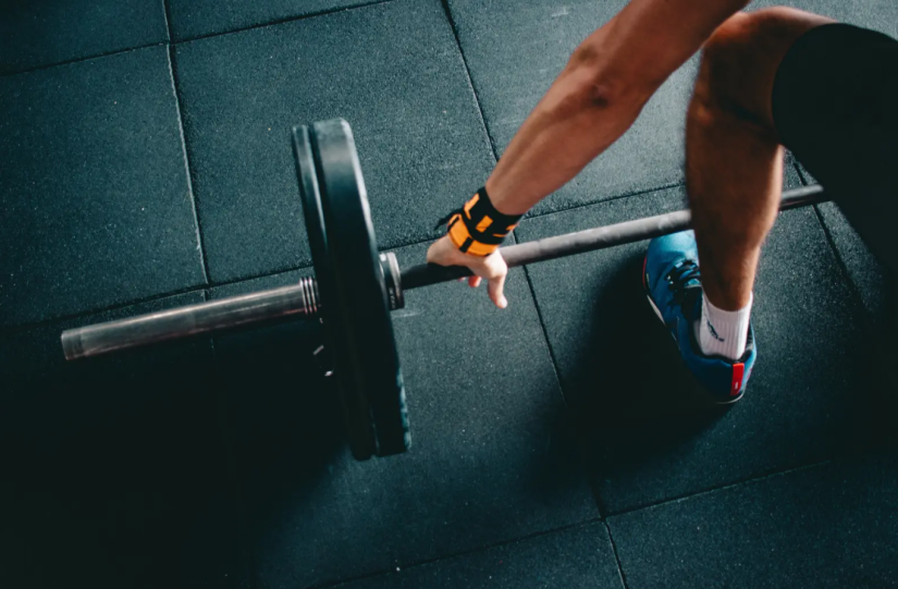 Photo of a man in a gym picking up a barbell