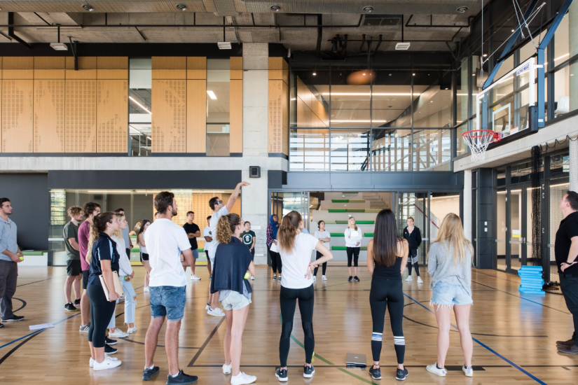 A group of students watching another student play basketball