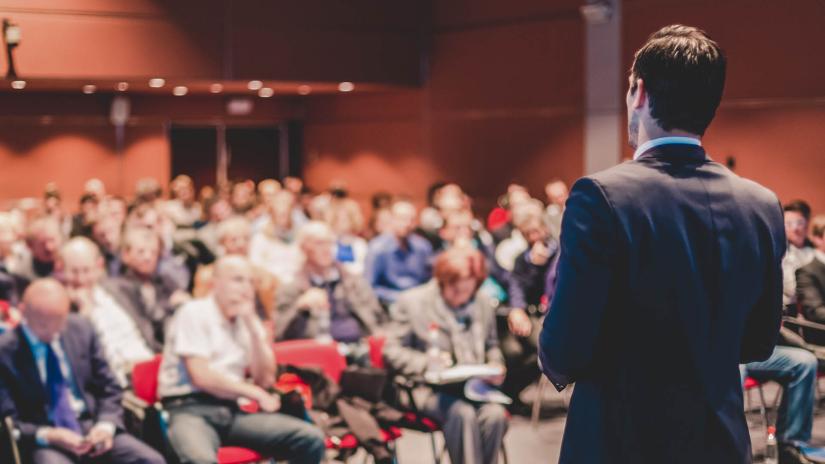Speaker in front of a crowd at a conference