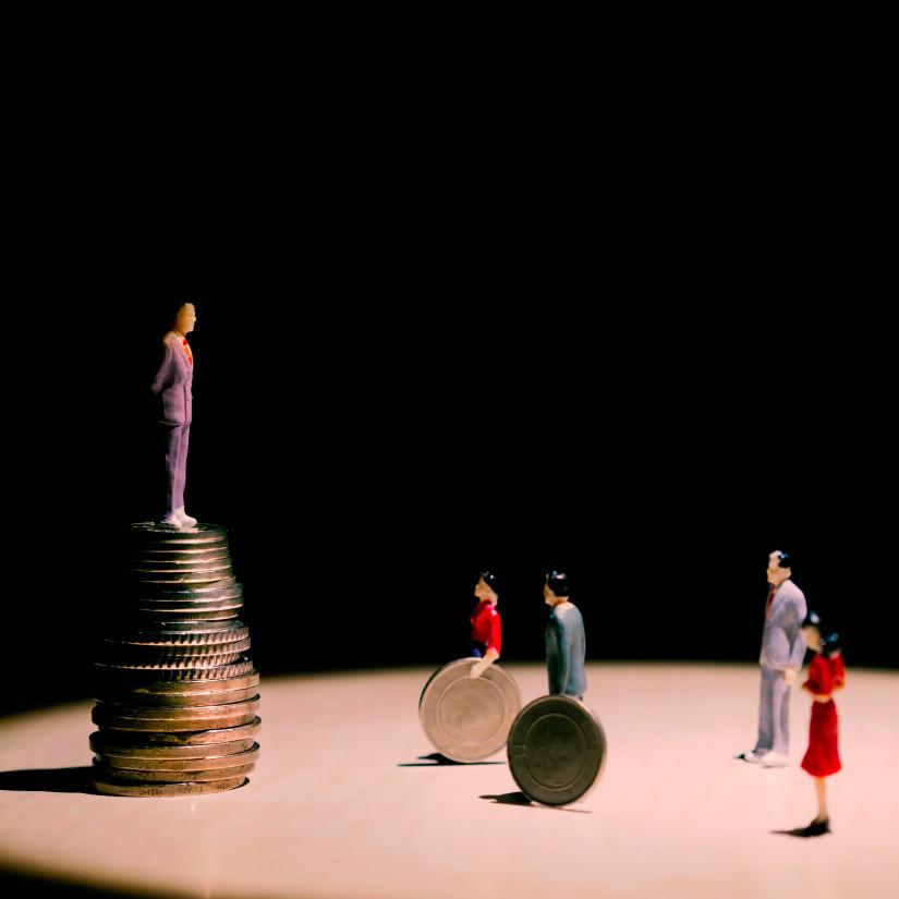 A man stands upon a pile of coins looking down at people below