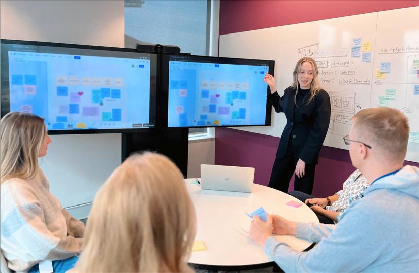 Natalie Johnson standing in an office meeting with four other professionals