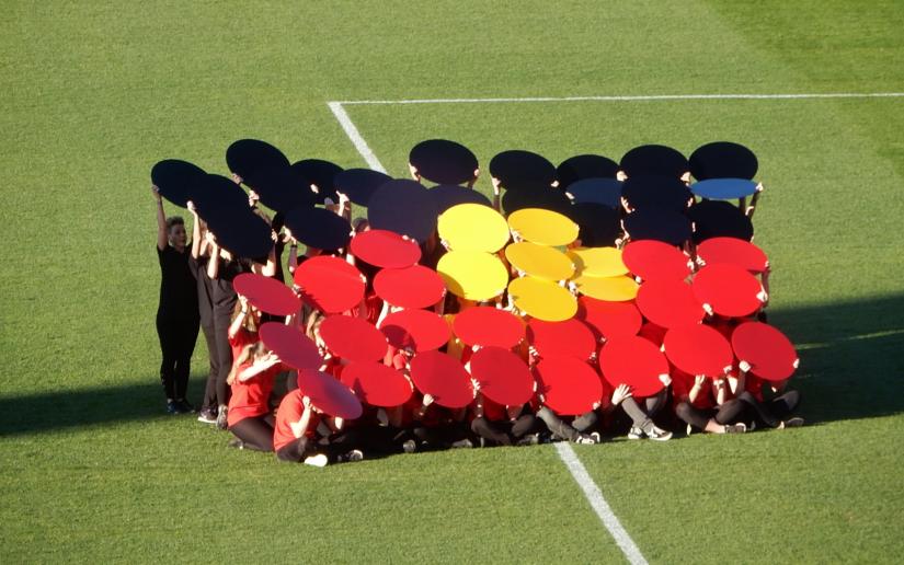 A group of people form an Indigenous flag using coloured cards at the Indigenous AFL round at the Adelaide Ova in June 2018. Picture by Michael Coghlan on Flickr (CC BY-SA 2.0)