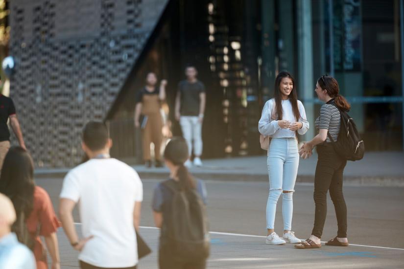 2 girls talking outside building 11