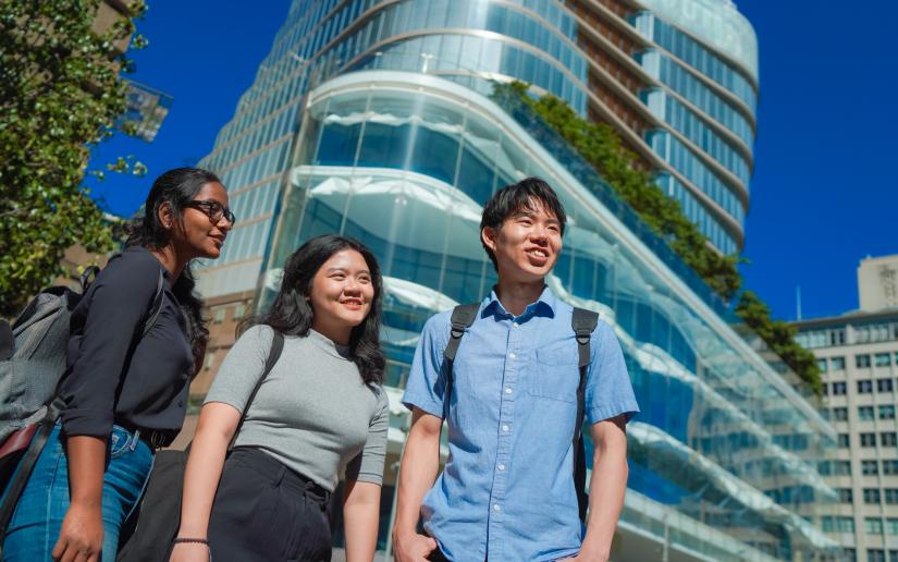 Three students stand in front of UTS Central looking out across campus.