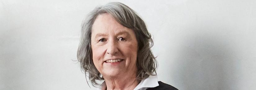 Distinguished Professor Jane Hall smiles at the camera in front of a white background.