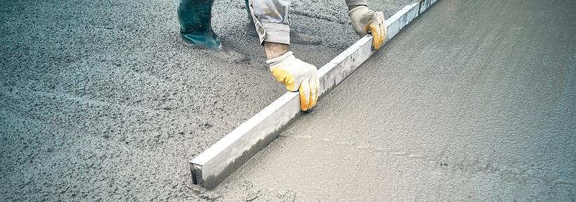 a construction worker levels wet concrete with a tool.