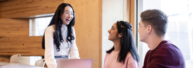 Undergraduate students laughing together in a classroom