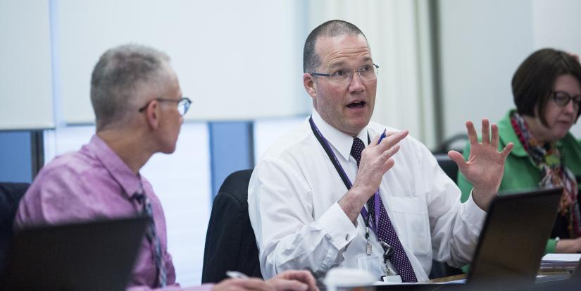 Three professionals sitting at a desk having a discussion