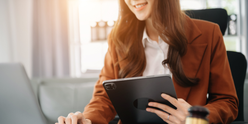 Image of a woman holding an ipad and typing