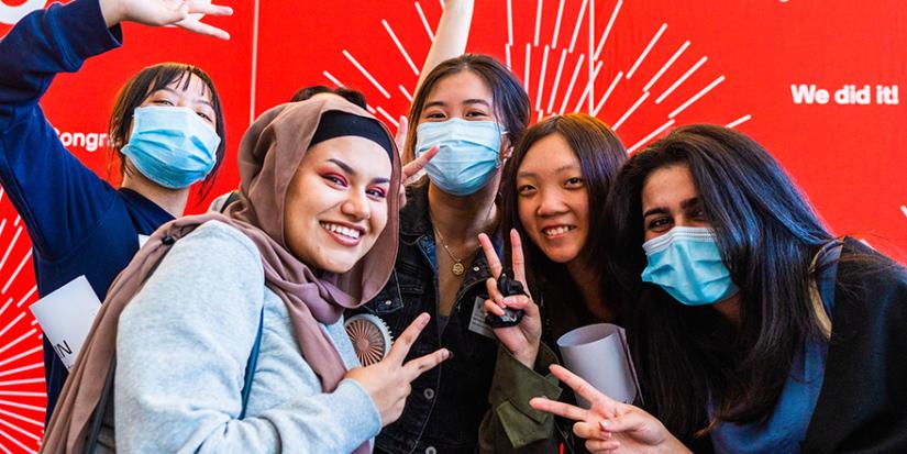 Female high school student posing in front of a red backdrop at their UTS U@Uni Academy graduation.