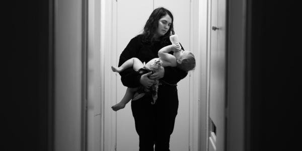 Mother holding a baby while they drink from a bottle.