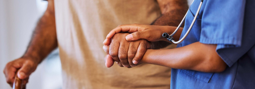 A nurse assisting an elder man walk