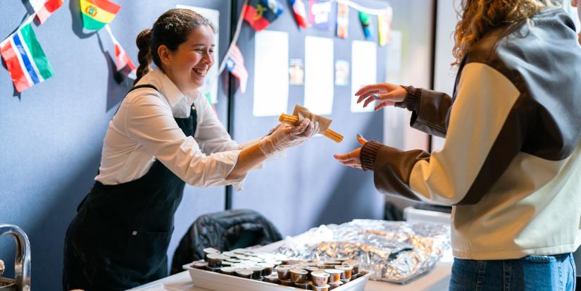 Churros being handed across a table of food