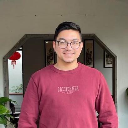 Man wear red sweater smiles into the camera.