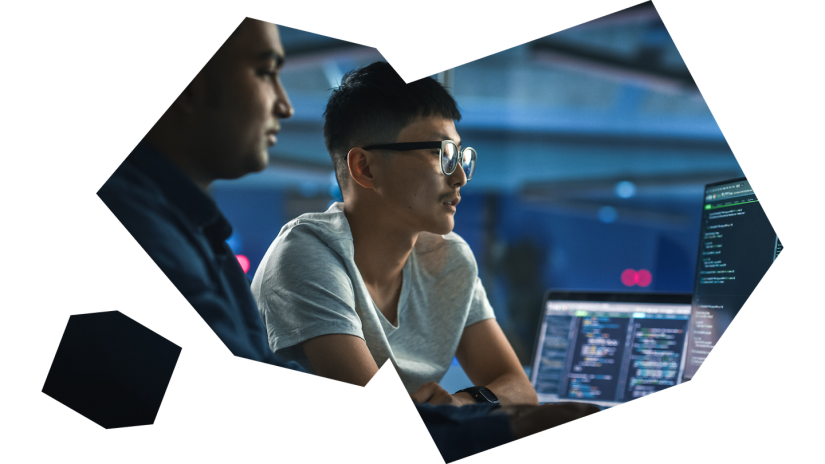 Two internatioanl students looking at computer with code on it.