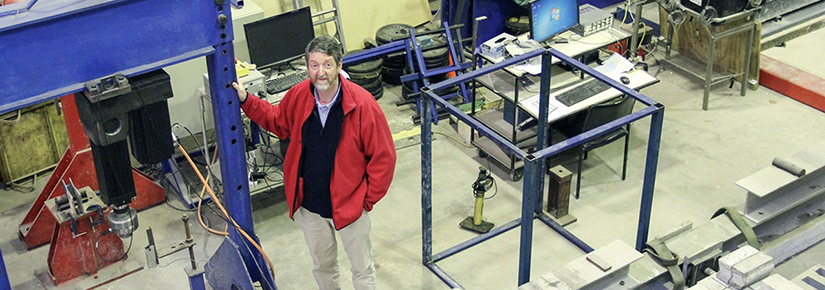 A man stands in a workshop, looking up at the camera