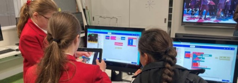 School children engaging in a design exercise on a tablet and computer.