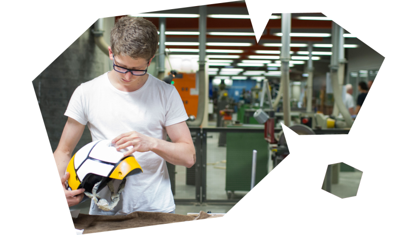 Students looks at helmet in fabrication workshop