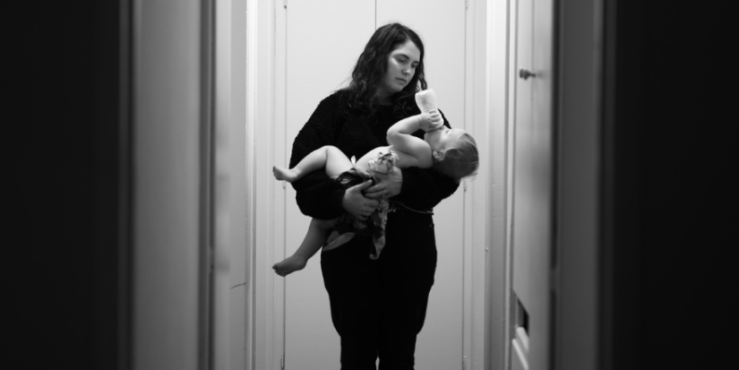 Mother carrying her baby while it drinks out of a bottle.