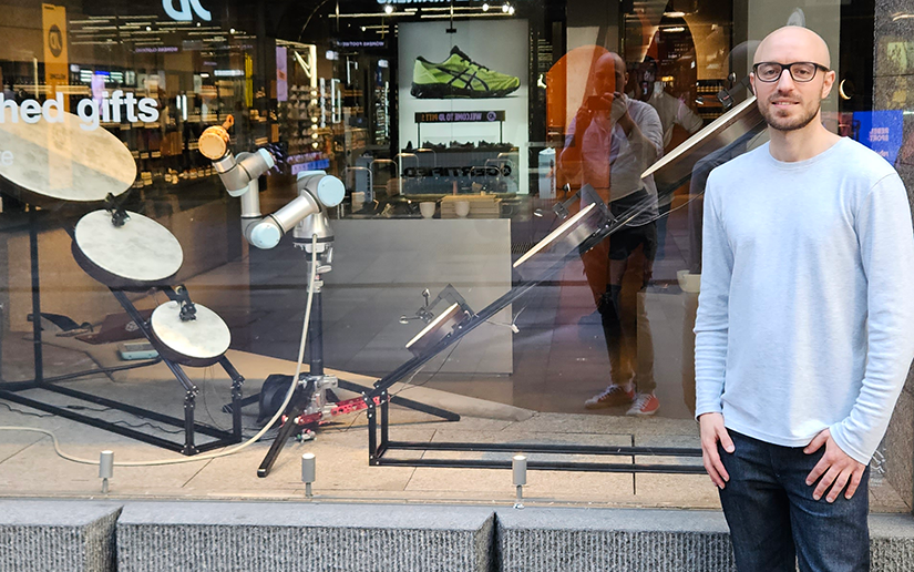 Dr Fred Sukkar stands outside the shopfront next to the mechatronic music ensemble