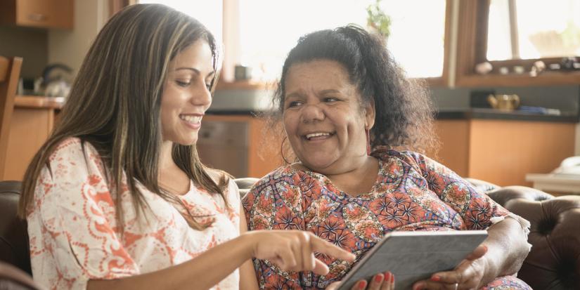 Two women sitting on a couch with an ipad