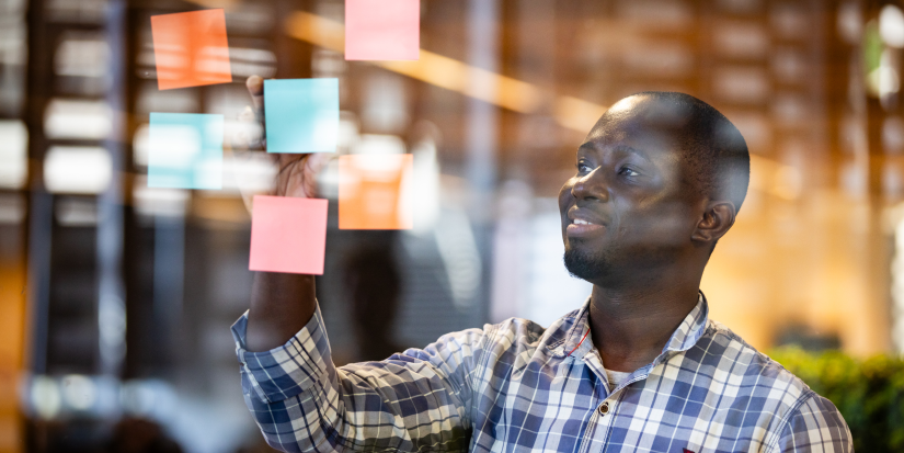 PhD student adding sticky notes to a wall