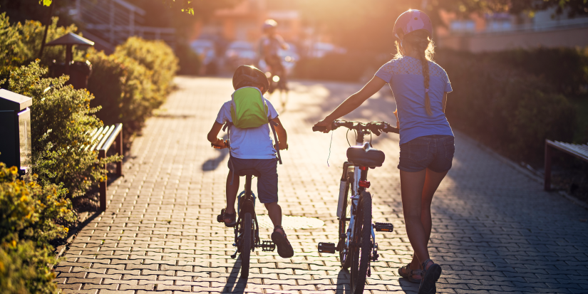 Three kids returning home from a bike trip. Kids are riding on the residential area walkway. Kids are aged 8 and 11.