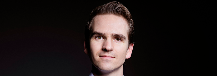 Well-groomed young man with dark hair in business attire looking at camera