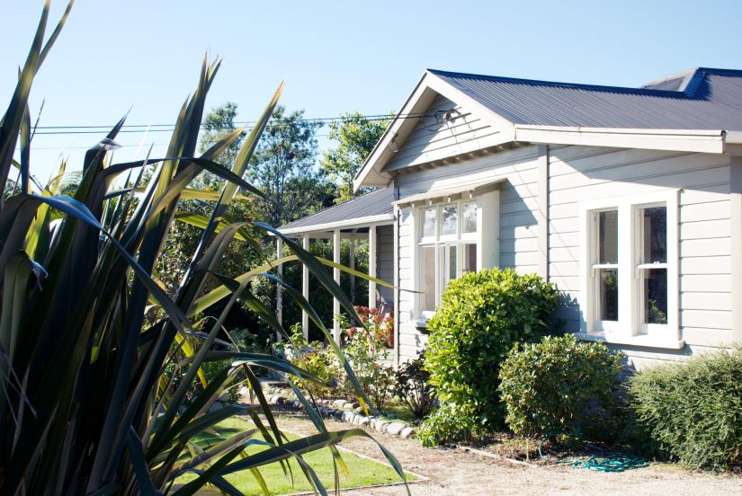 A house in the sunshine with surrounding greenery.
