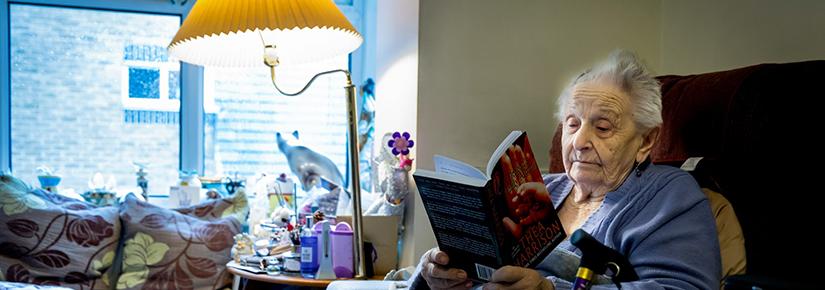 Rights free picture of an elderly woman reading in a chair with a blanket over her knees