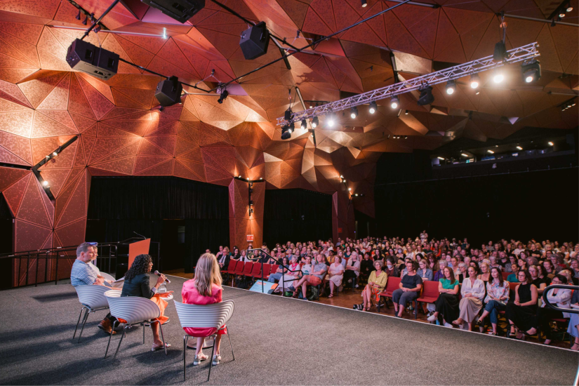 Photo of the speakers and a full house at IWD 2024