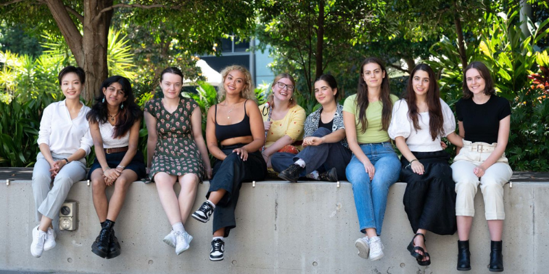 a line of people sitting in a row and smiling