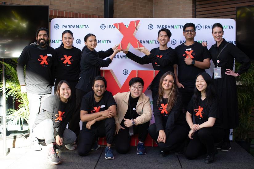 A group of young people in black Ted X Tshirts smiling at the camera