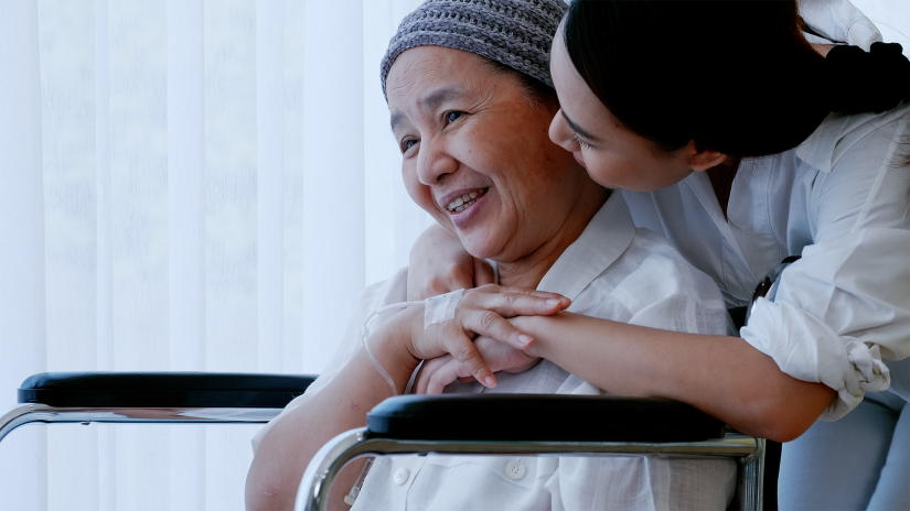 Mother in wheelchair wearing head scarf is being hugged by her daughter