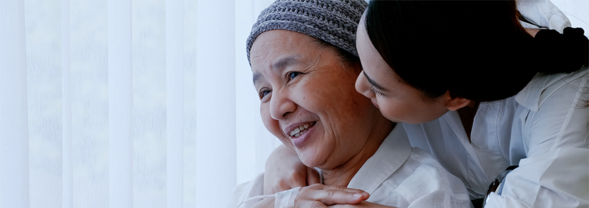 Mother in wheelchair wearing head scarf is being hugged by her daughter