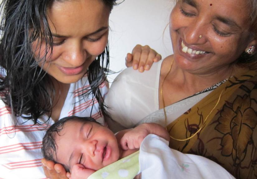 Women looking at a newborn baby