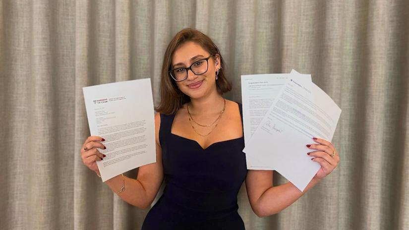 Jaya Dadwal holding up successful acceptance letters from U.S. universities