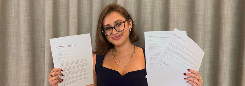 Jaya Dadwal holding up successful acceptance letters from U.S. universities