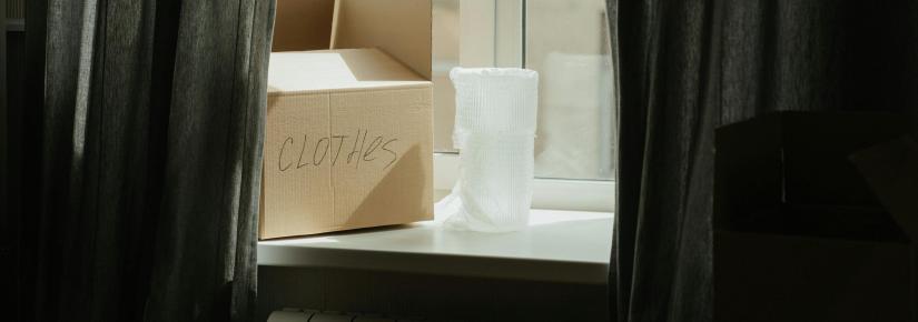 A cardboard box marked 'clothes' sits on a windowsill.