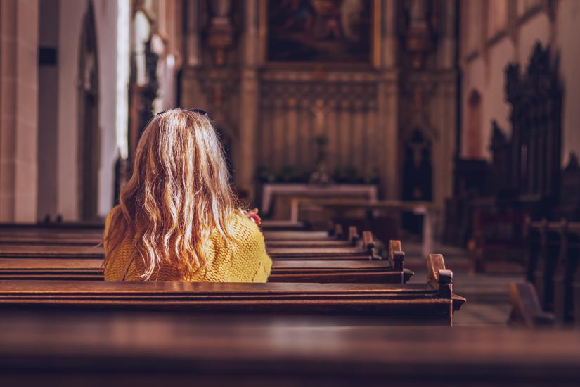 Woman sitting in a church. Adobe Stock image