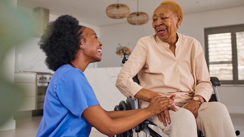 A healthcare worker talking to a patient in a wheelchair